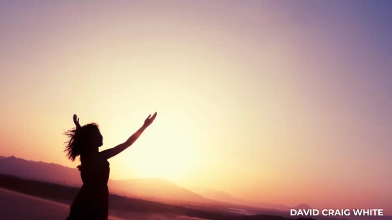 Silhouette of a woman with open arms at sunset, symbolising freedom and a simplified approach to work.